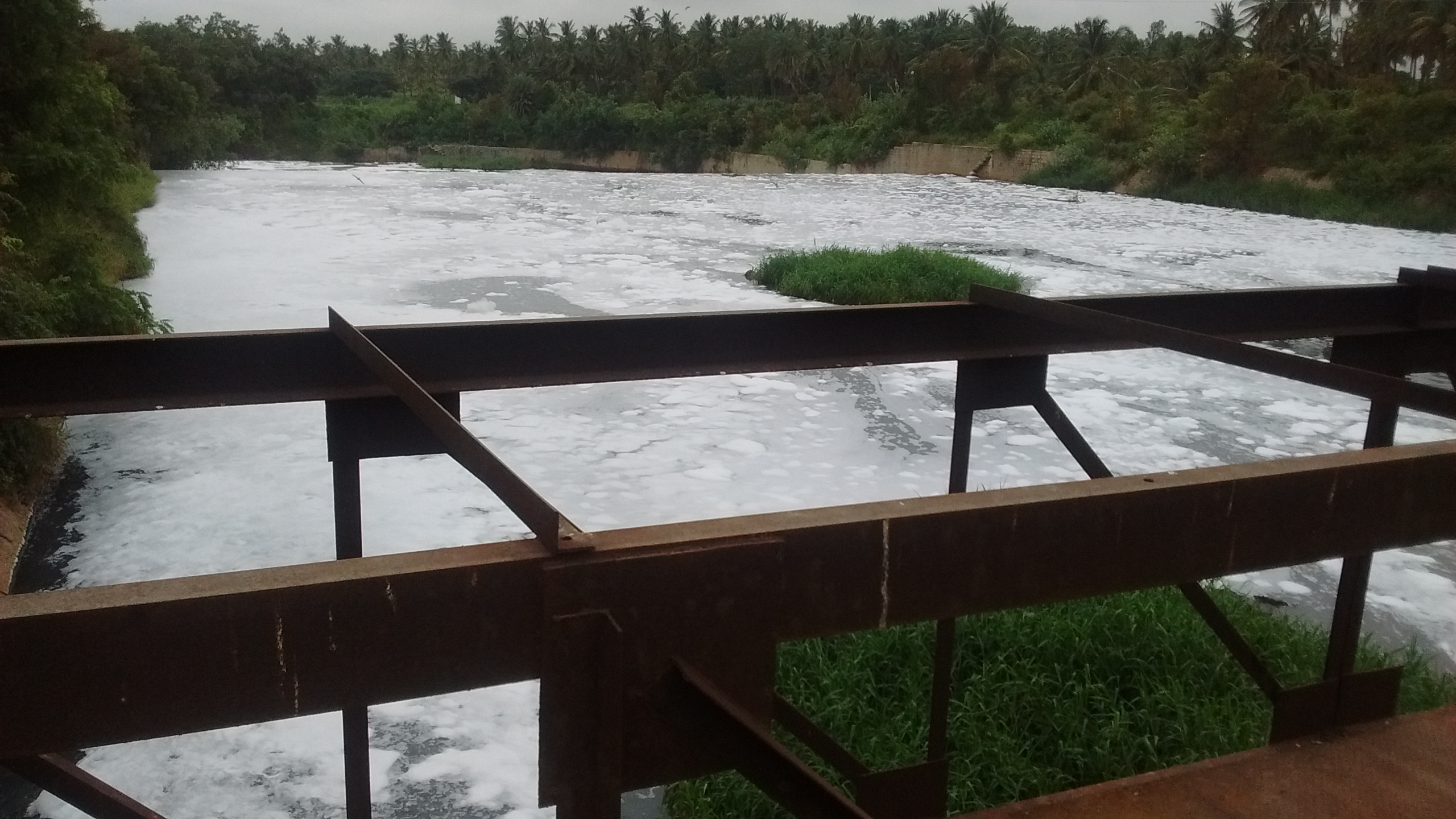 Polluted Water with foam going down the river, as seen from the bridge